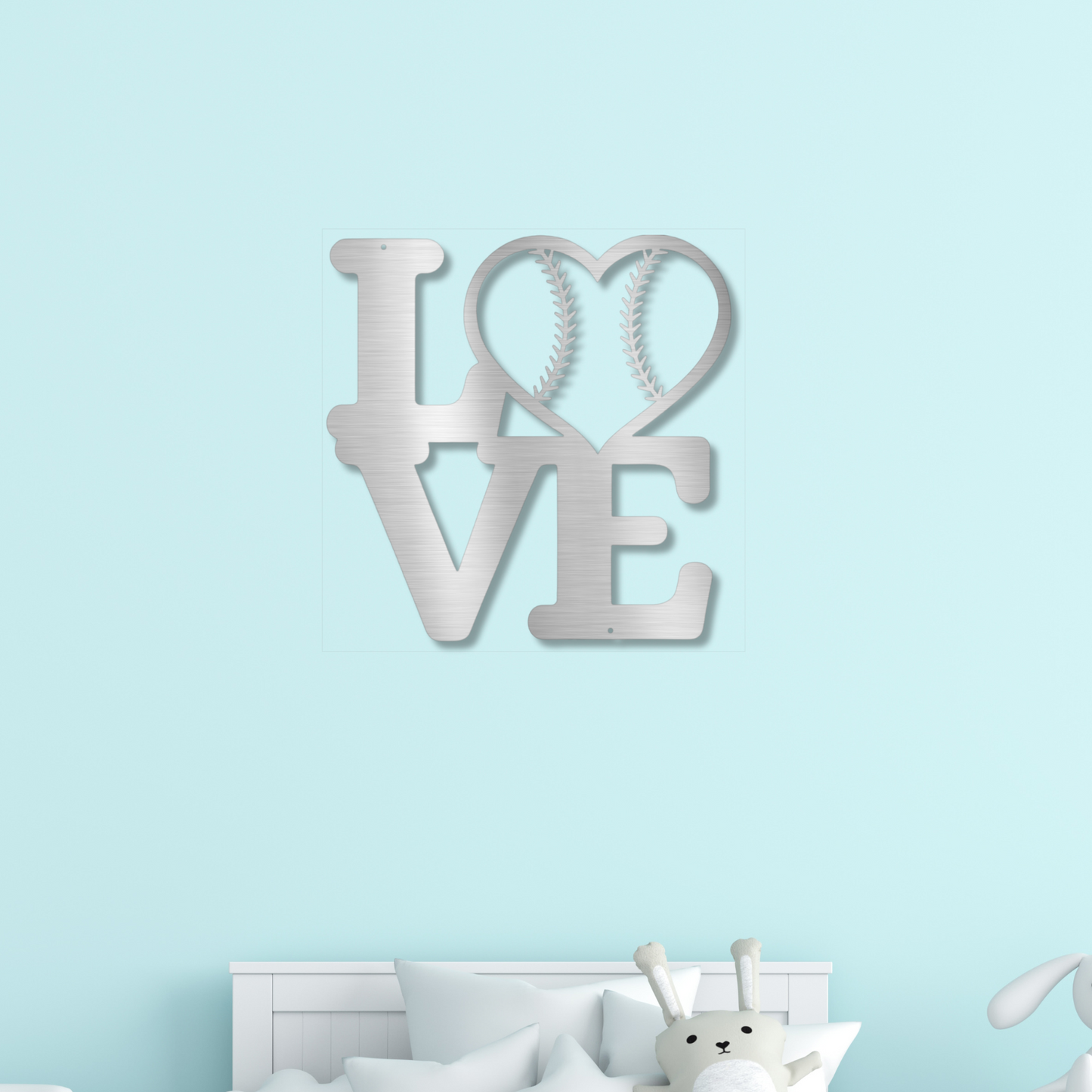 Silver metal "LOVE" art with baseball/softball seams in heart shaped "O" on a light blue wall.