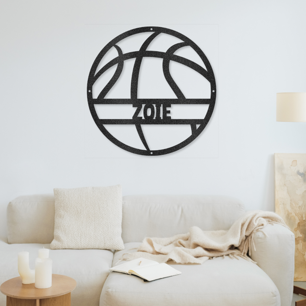 Black metal wall art with the name Zoie on a white wall above a beige sofa.