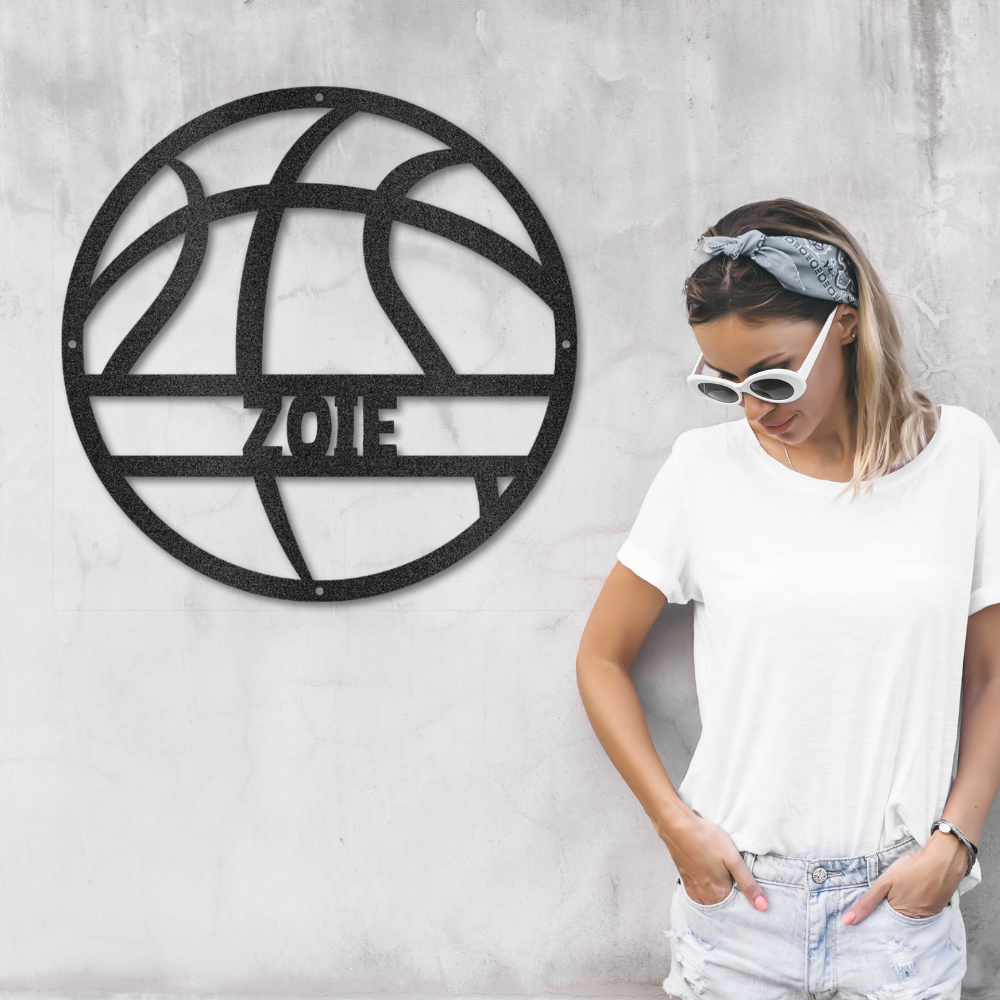 Woman standing next to a decorative wall art piece with 'Zoie' on a gray wall.